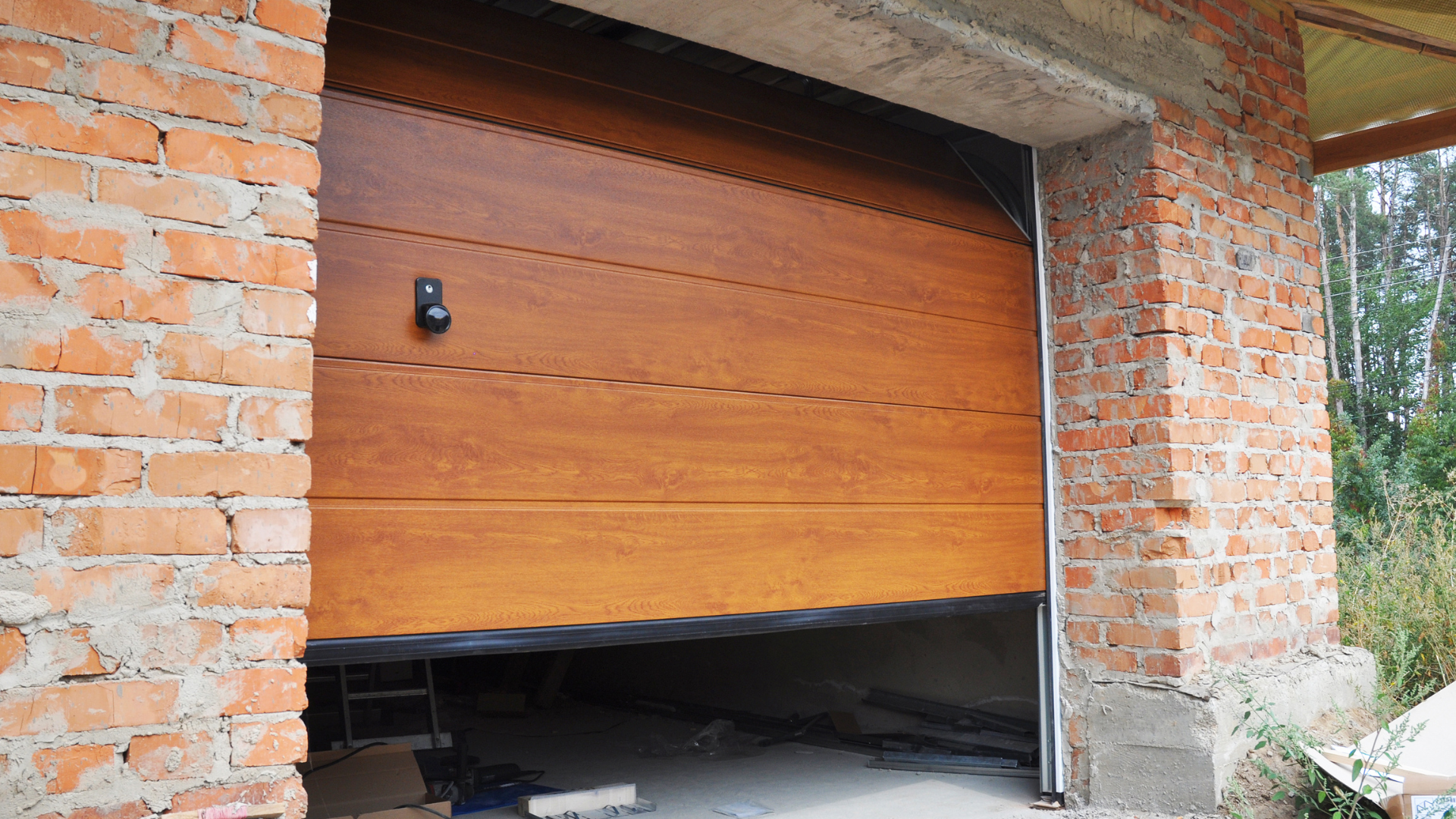 A wooden garage door is open in a brick building.
