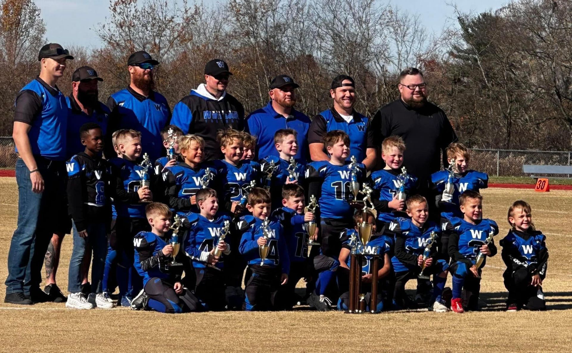 A group of young football players are posing for a picture on a field.