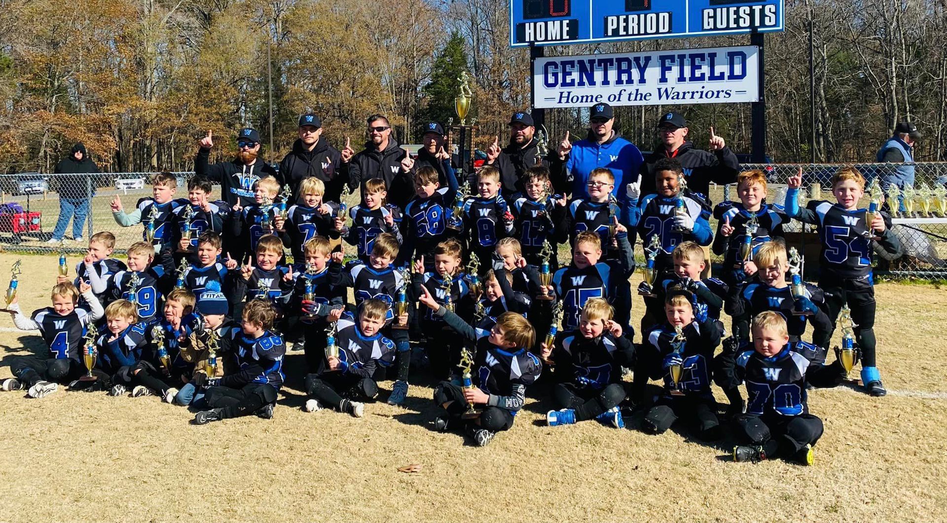 A group of children are posing for a picture in front of a sign that says gentry field