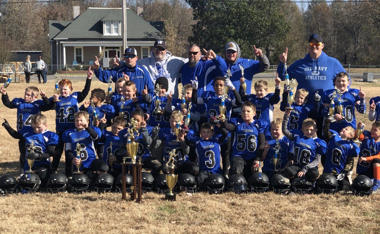 A group of young football players are posing for a picture on a field.
