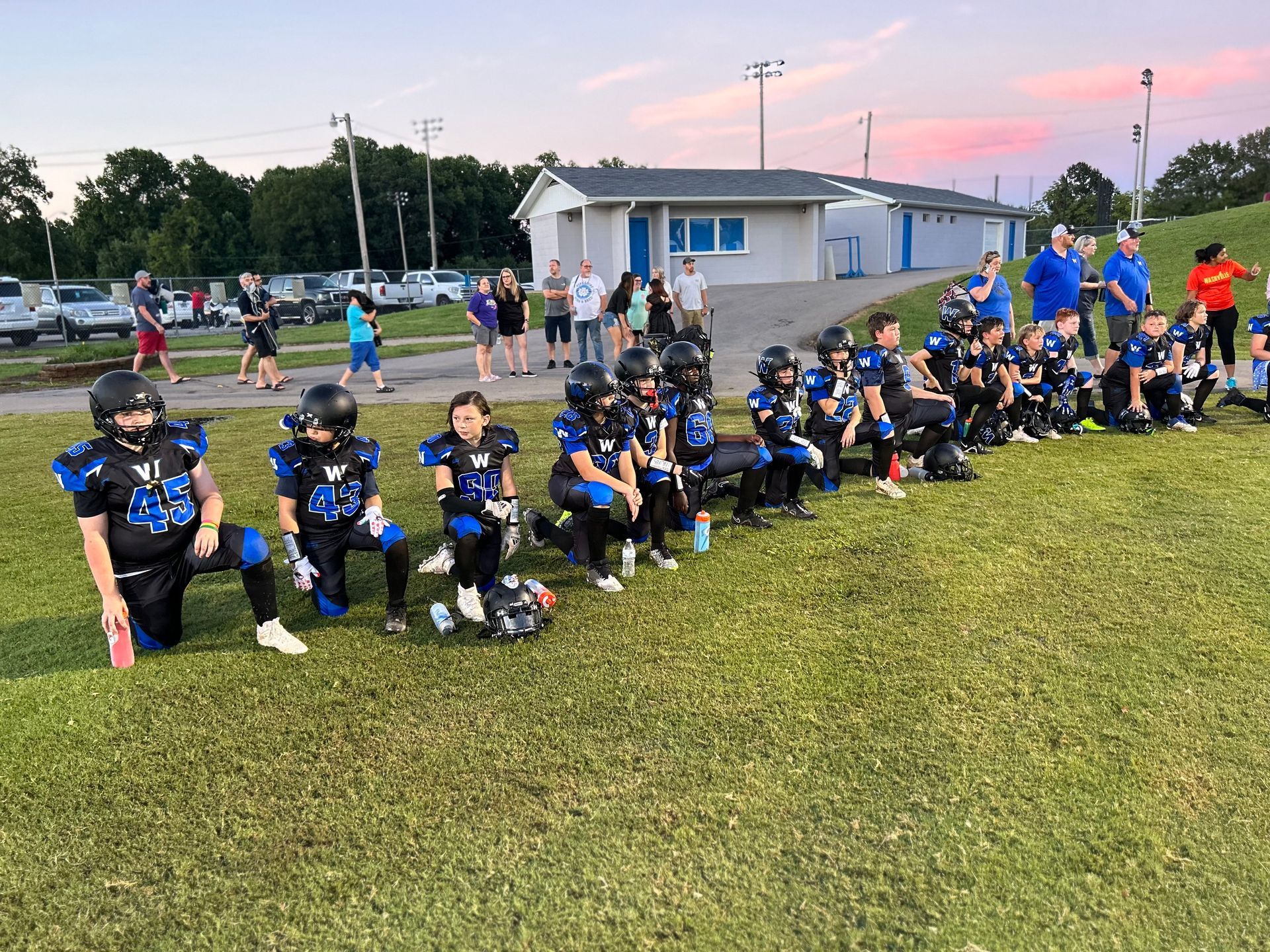 A group of young football players are kneeling on the field.