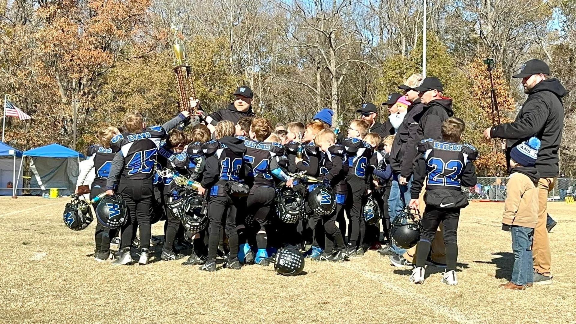 A group of children are standing in a huddle on a football field.