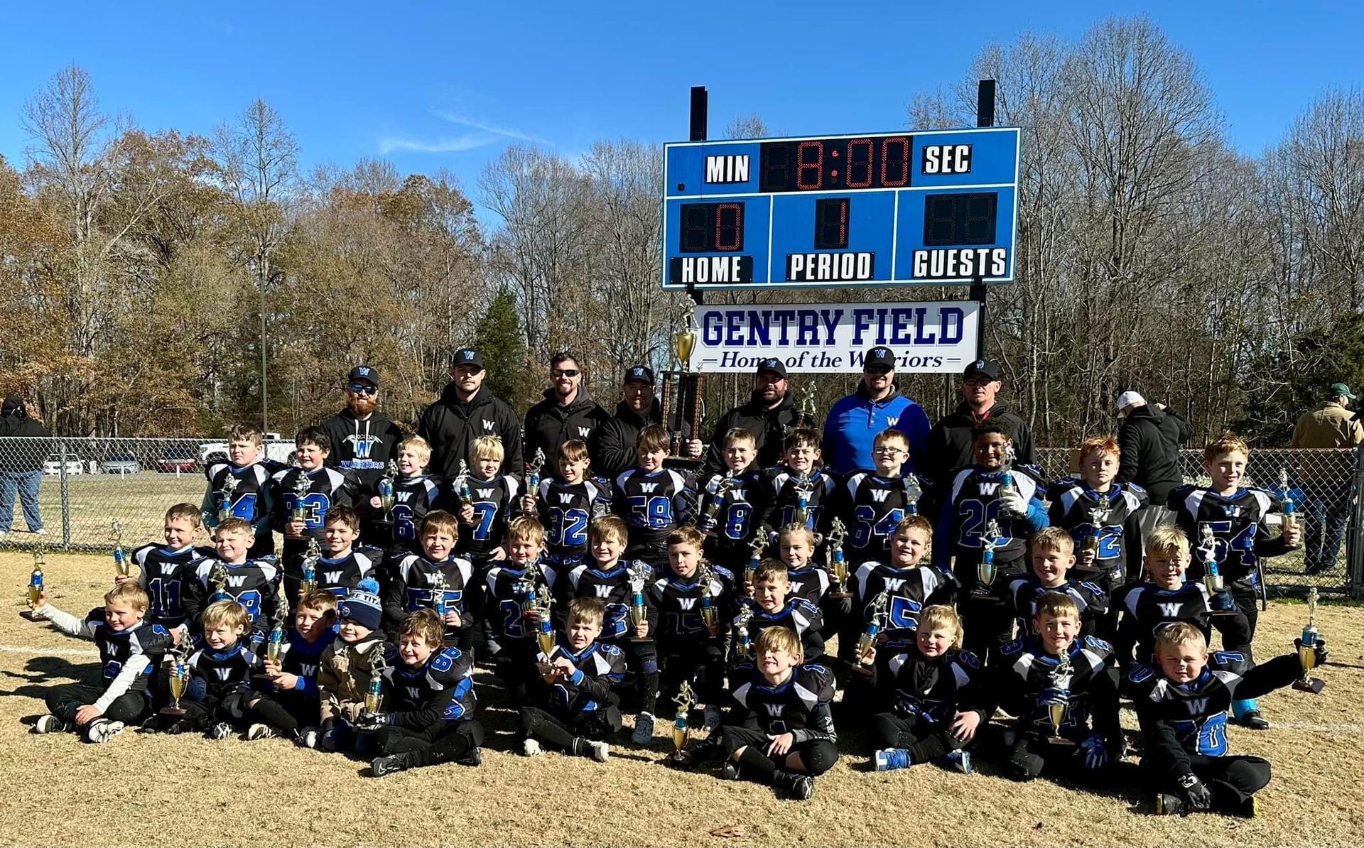 A group of young boys are posing for a picture in front of a scoreboard.