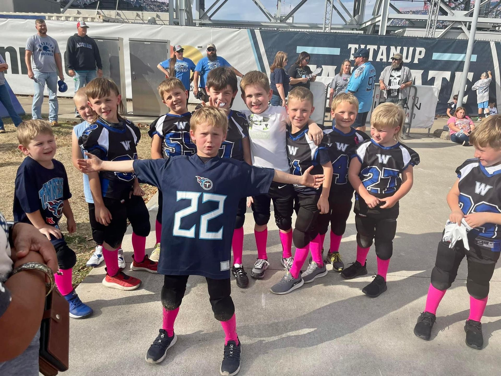 A group of young boys are posing for a picture and one of them is wearing a titans jersey.
