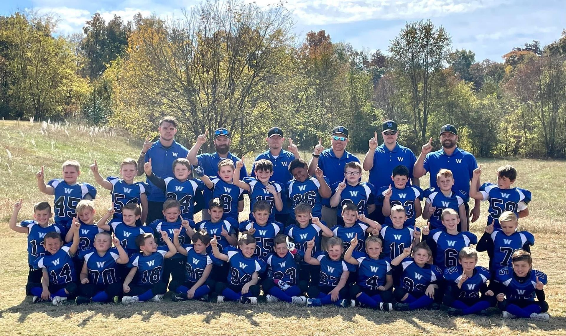 A group of young football players are posing for a picture on a field.