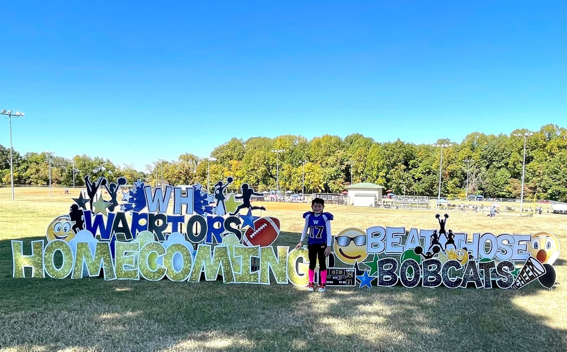A group of people are standing in front of a homecoming sign.