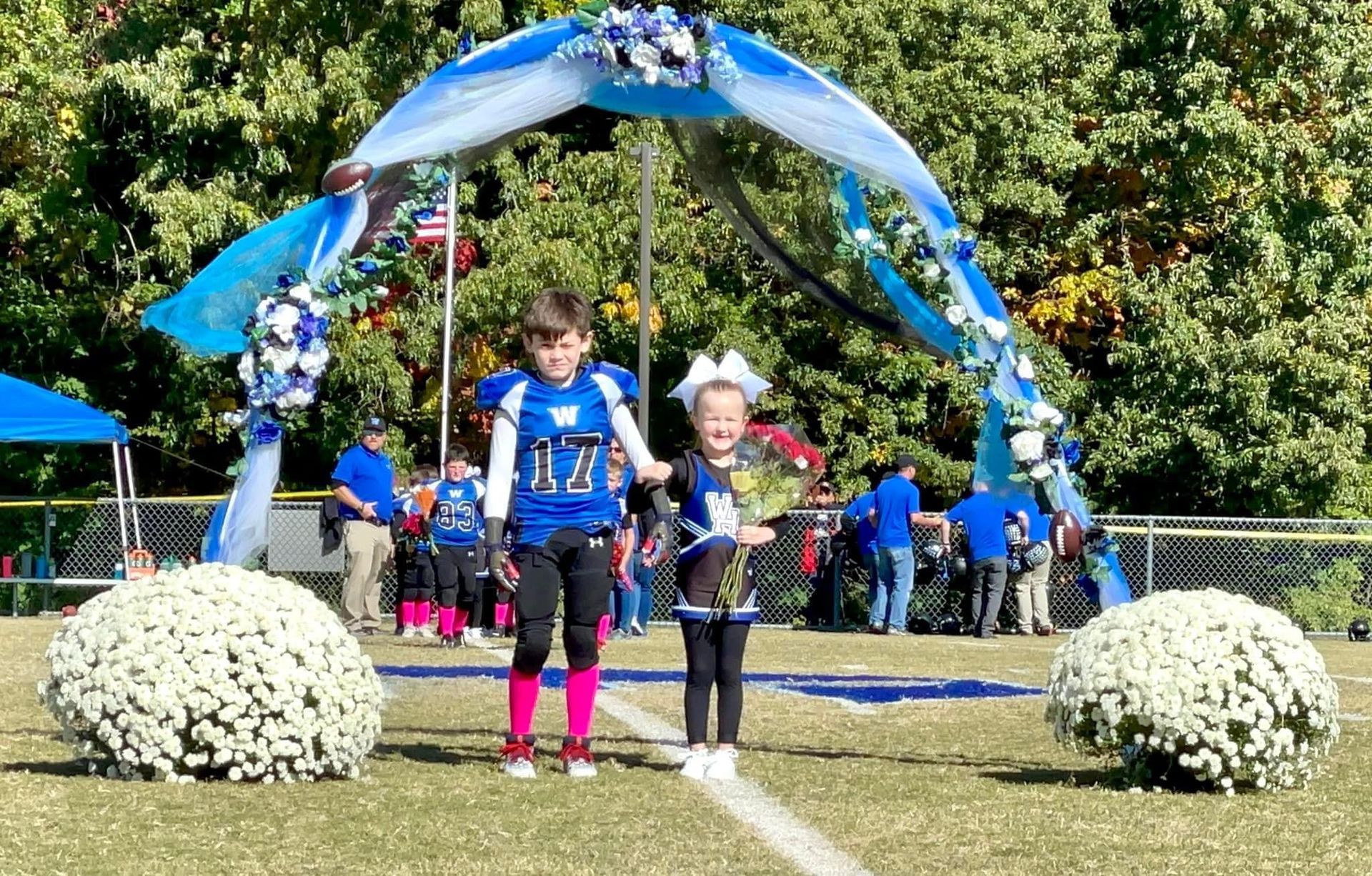 A boy and a girl are walking on a football field.