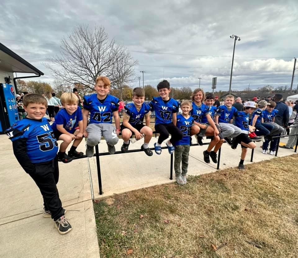A group of young boys are posing for a picture on a sidewalk.
