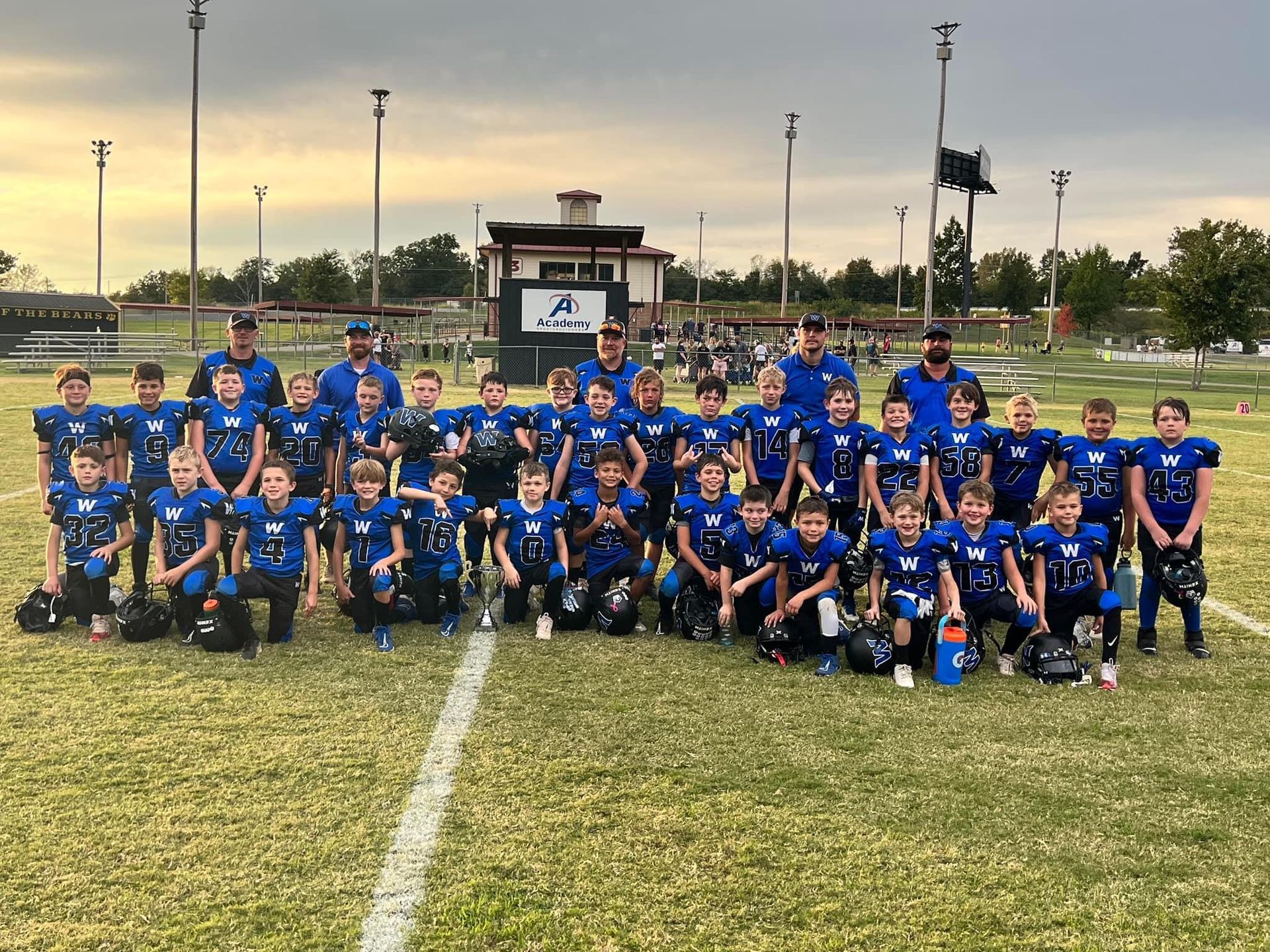 A group of young boys are posing for a picture on a football field.