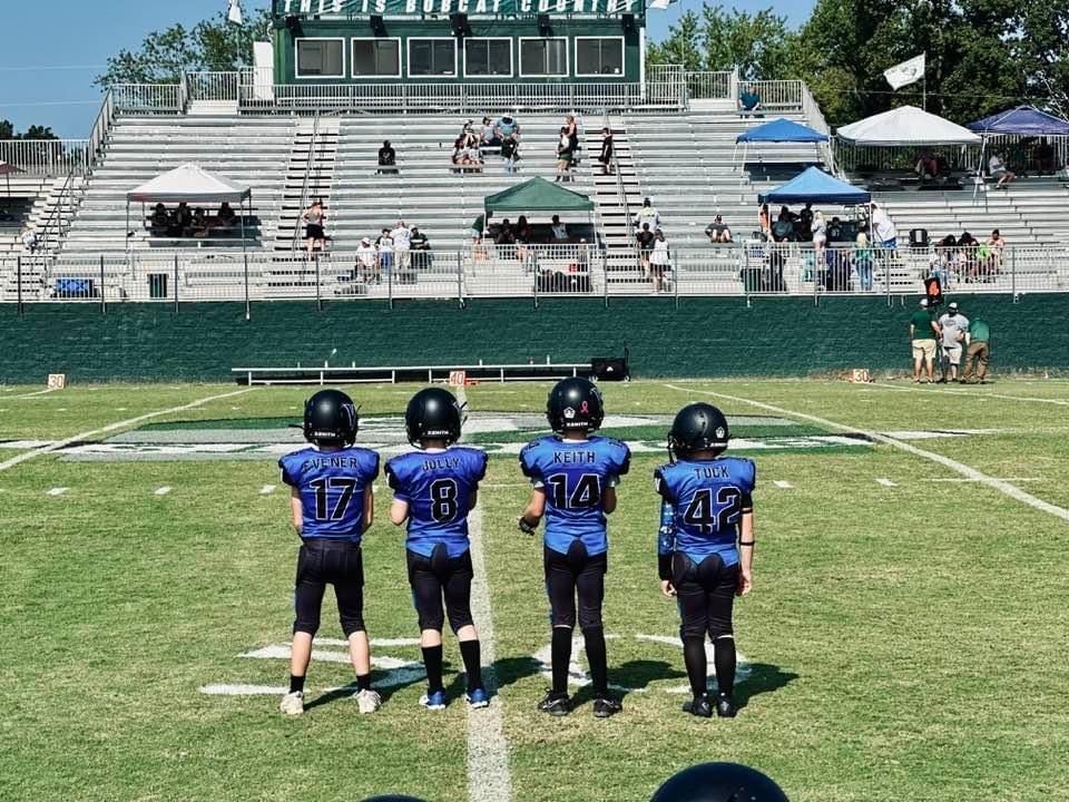 A group of young boys are standing on a football field.