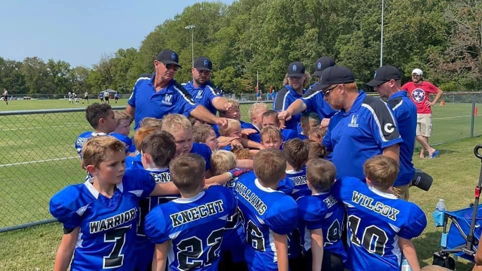 A group of young boys are standing in a huddle on a football field.