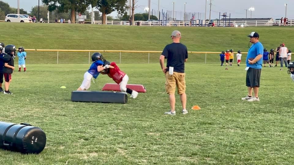 A group of people are playing a game of football on a field.