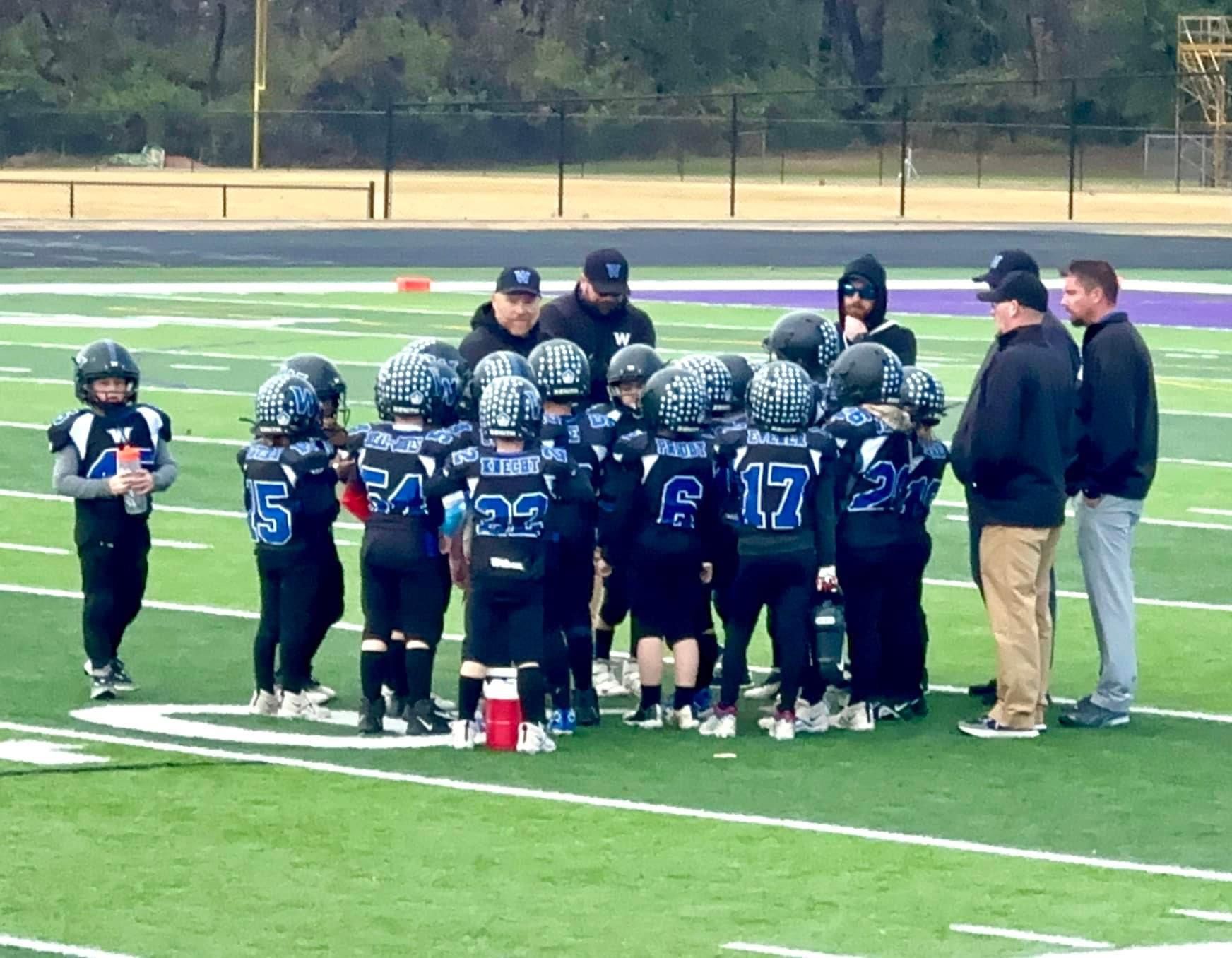 A group of football players are huddled together on the field
