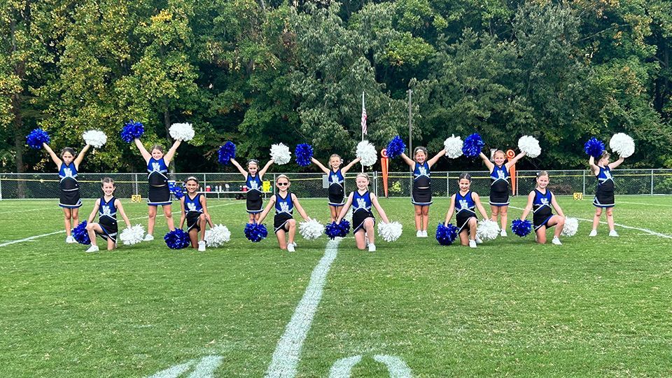 A group of cheerleaders are posing for a picture on a field.