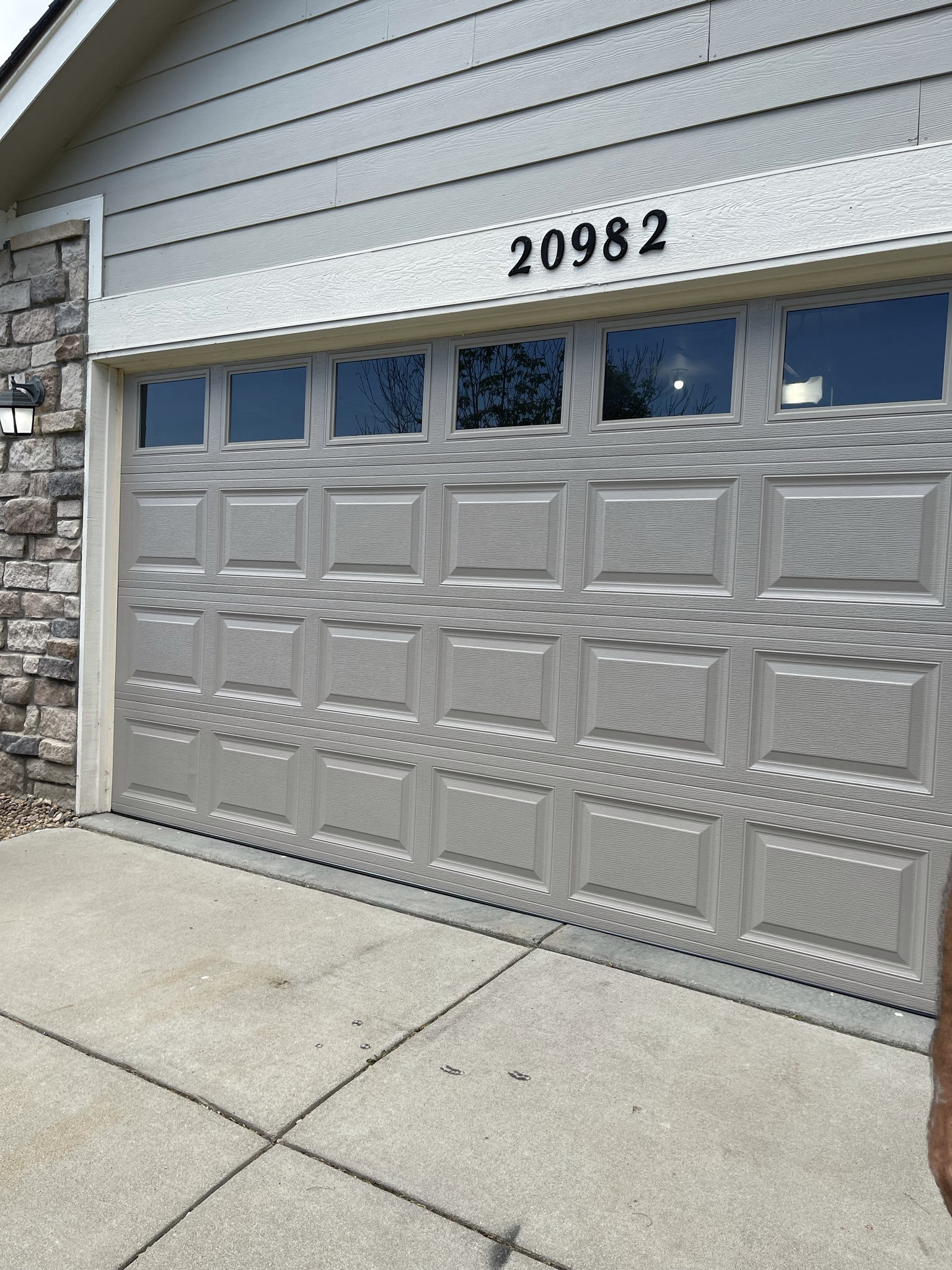 A person is standing in front of a garage door with the number 20982 on it.