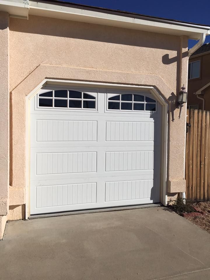 A white garage door is sitting on the side of a house.
