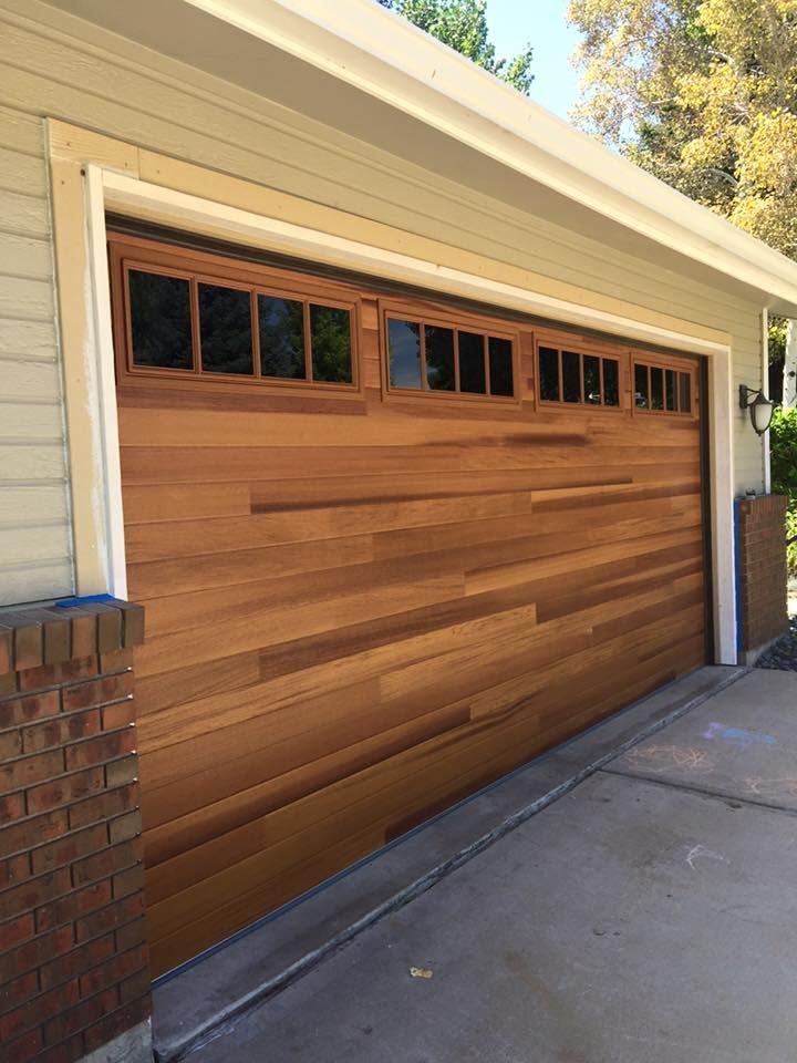 A wooden garage door is sitting on the side of a house.