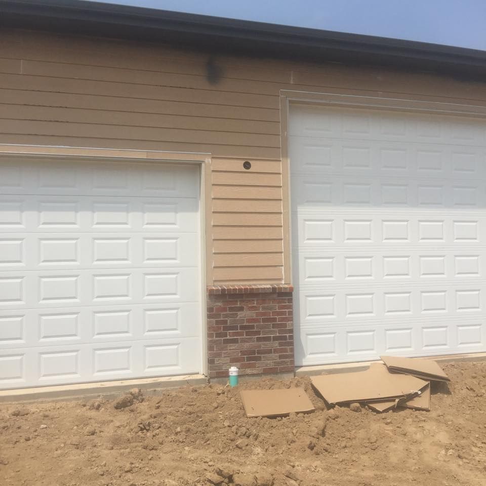 A house with two white garage doors and a brick wall