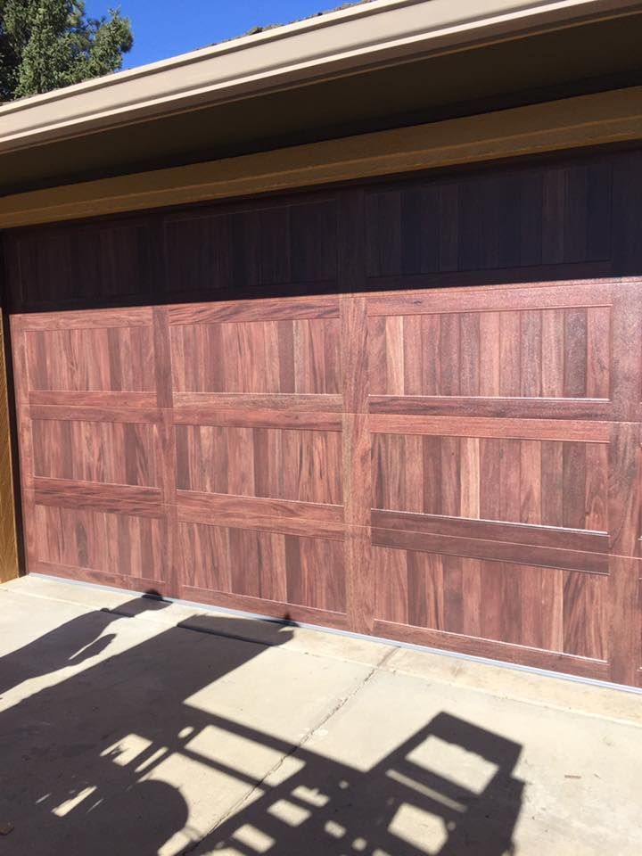 A wooden garage door with a shadow on the ground