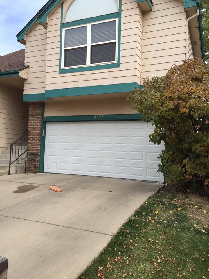 A house with a white garage door and a green trim