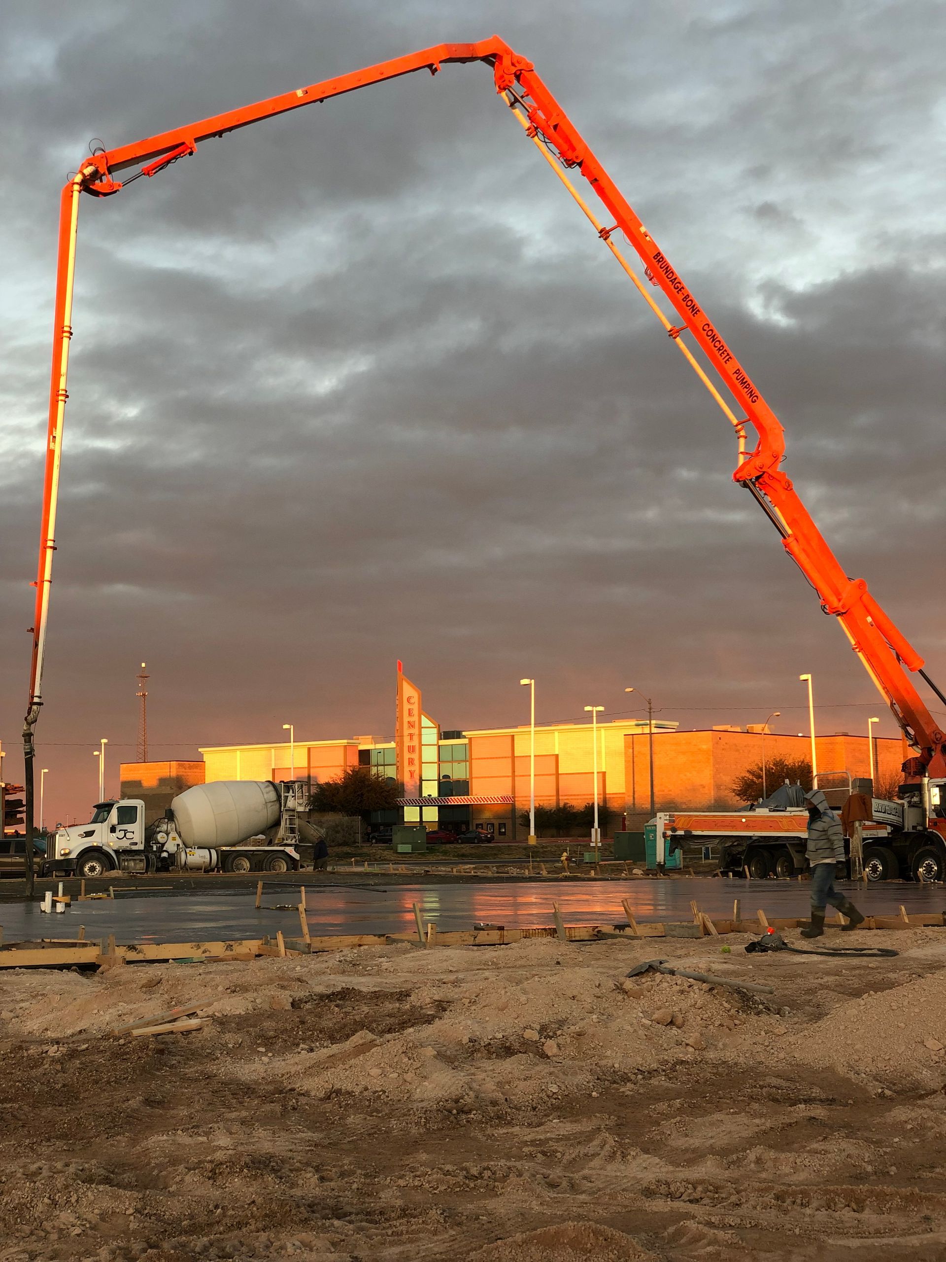 Modern building with silver facade, glass tower, and green-trimmed windows under blue sky.