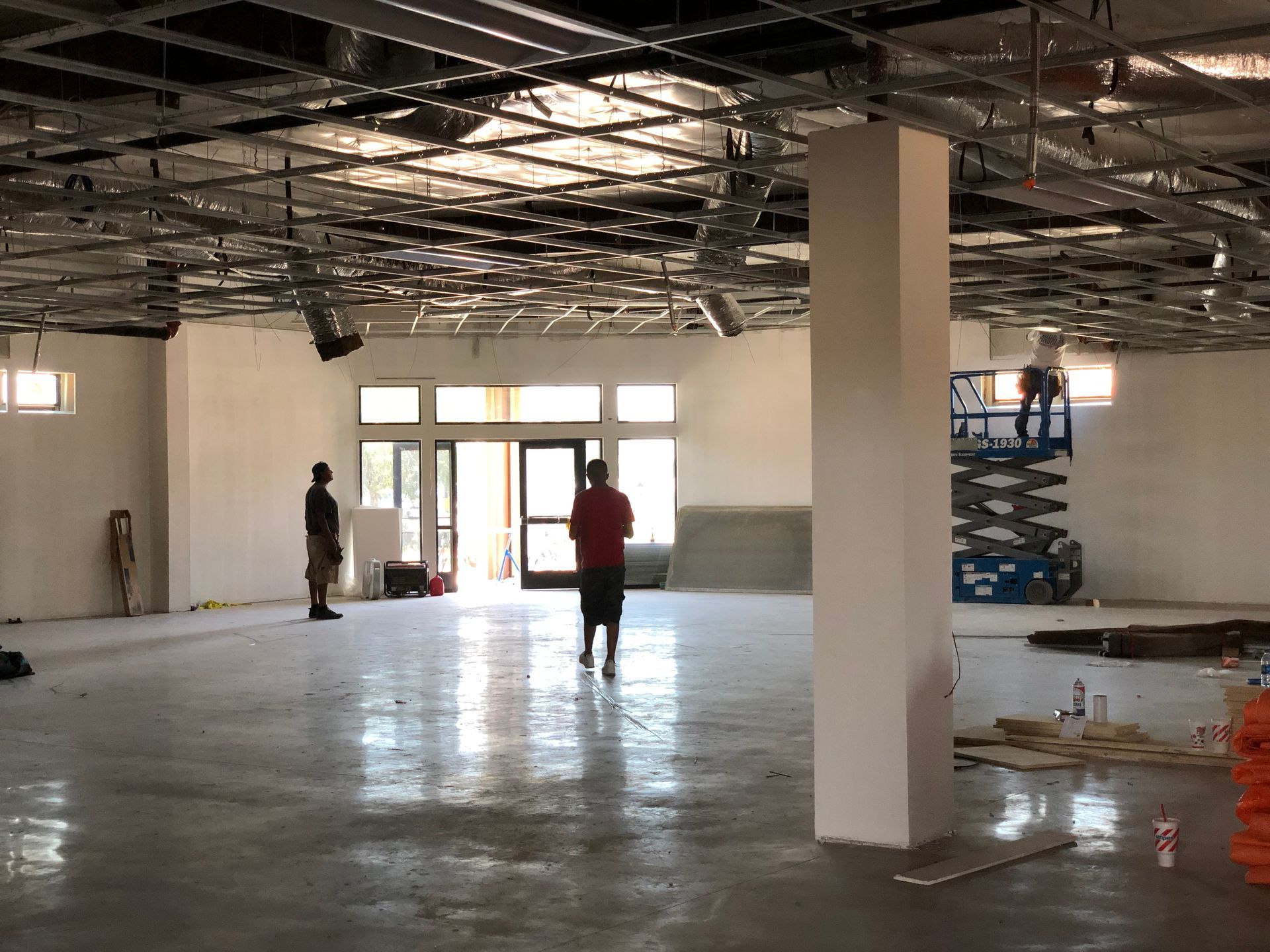Construction worker walks toward a crane at a building site, wearing safety gear.