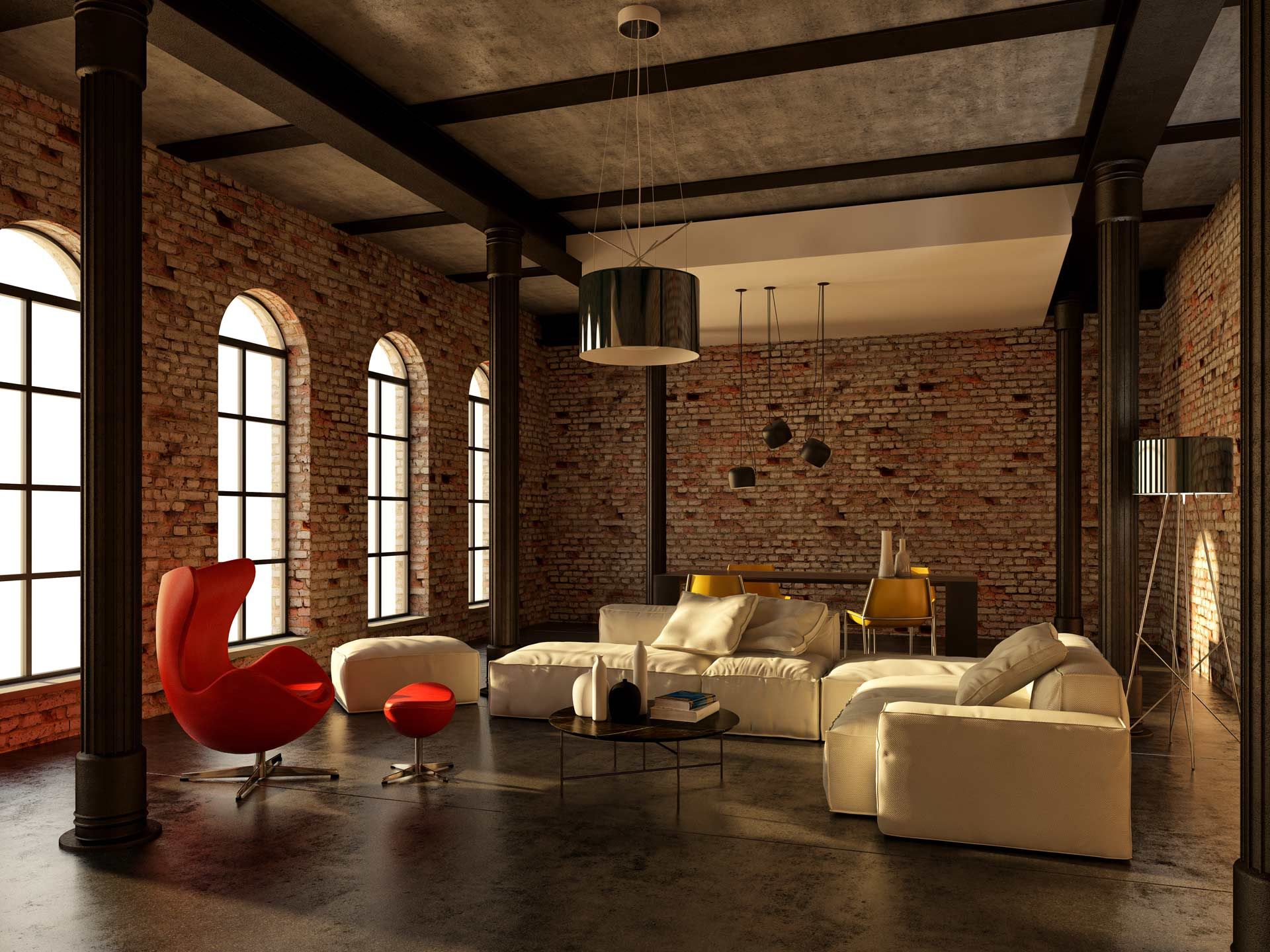 Loft interior with brick walls, large windows, leather seating, and a red chair.