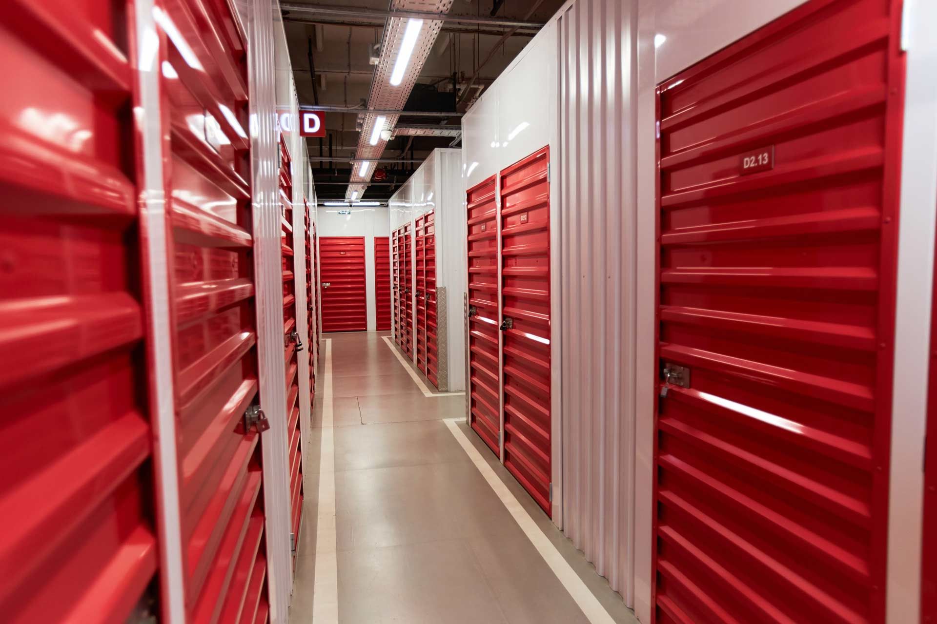 Red storage unit doors line a hallway; bright, clean interior.