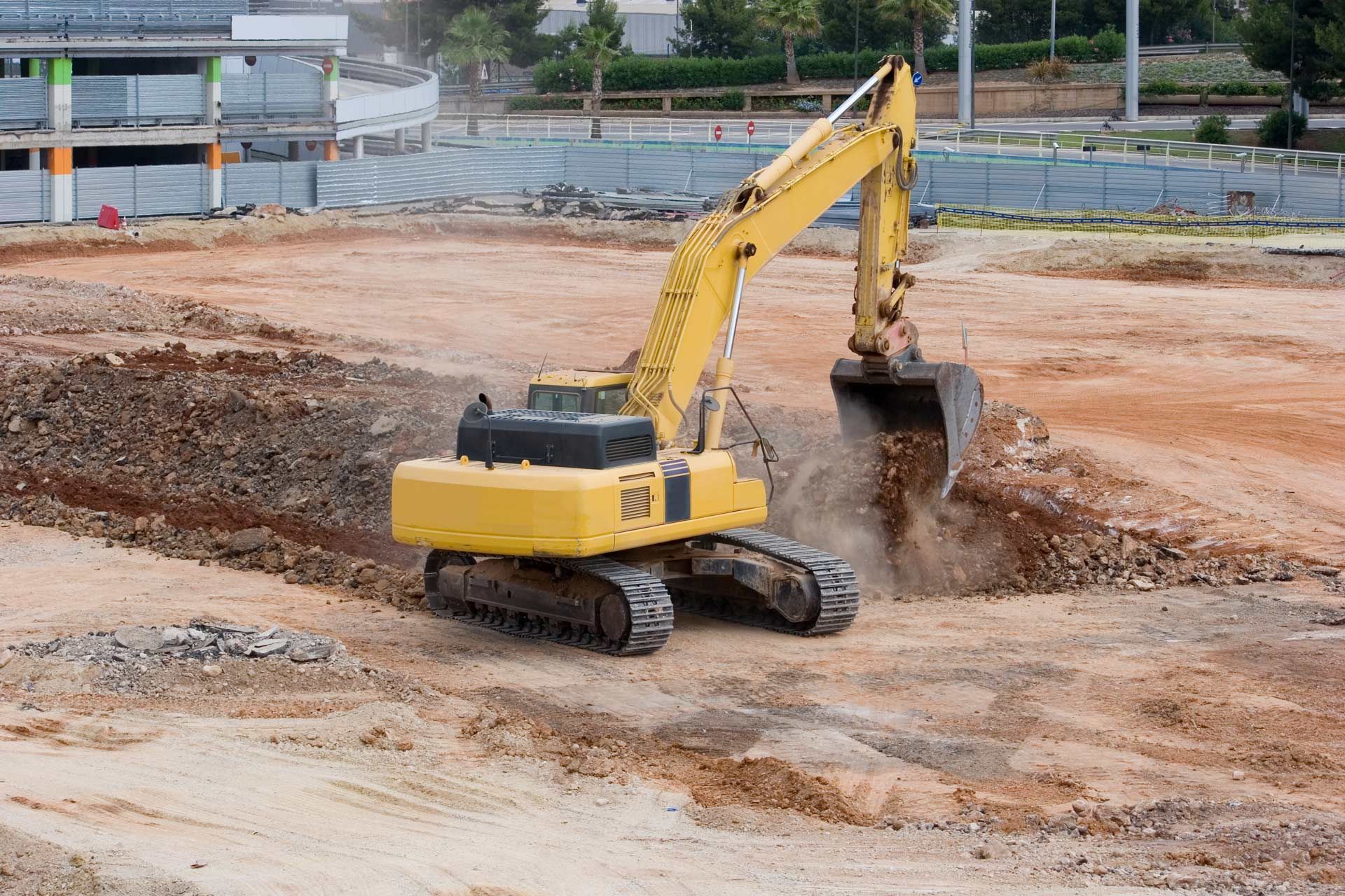 Yellow excavator digging in dirt at a construction site.