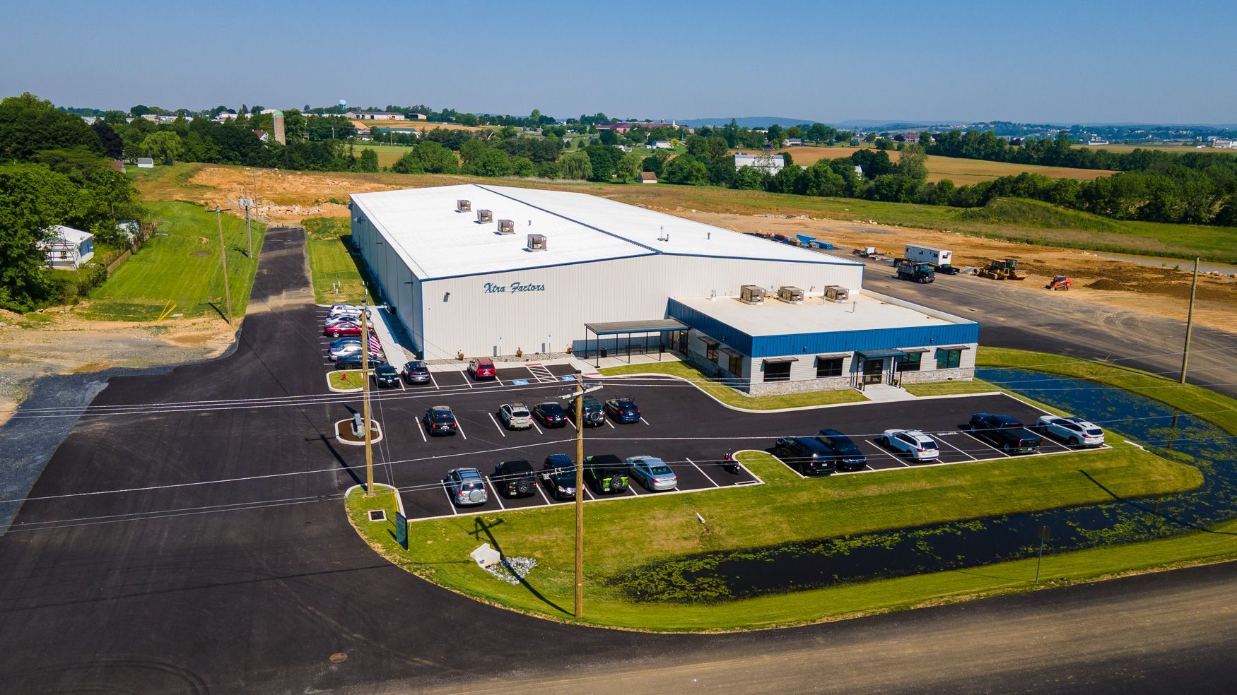 An aerial view of Xtra Factors East Earl, PA building with a lot of cars parked in front of it.