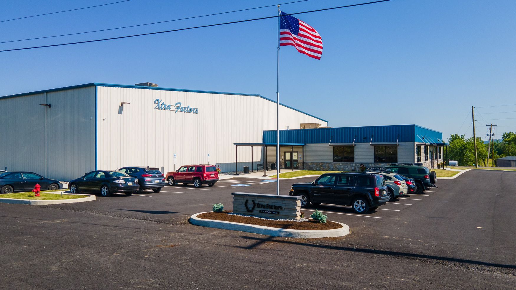 An american flag is flying in front of the Xtra Factors East Earl, PA building.