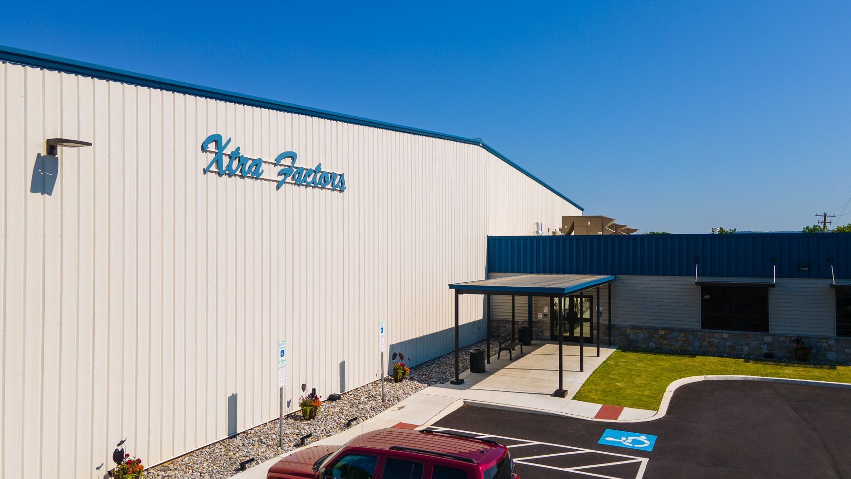 Xtra Factors East Earl, PA building with a blue roof and a red suv parked in front of it.