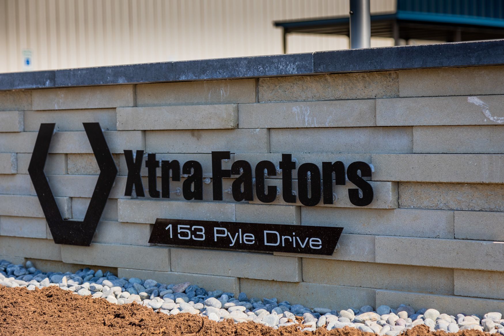A sign for xtra factors is on a brick wall