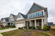 Row of suburban two-story houses with garages, blue shutters, and landscaped front yards