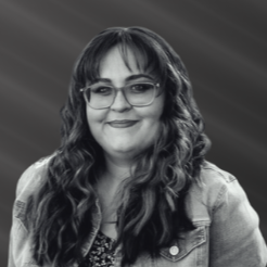 A black and white photo of a woman wearing glasses and a denim jacket.