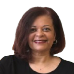 A woman with brown hair is wearing a black shirt and smiling.