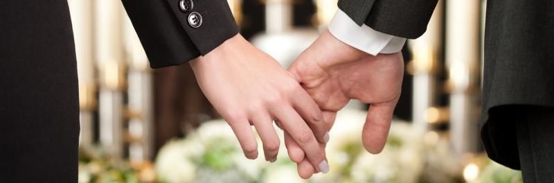 Two people in suits holding hands outdoors