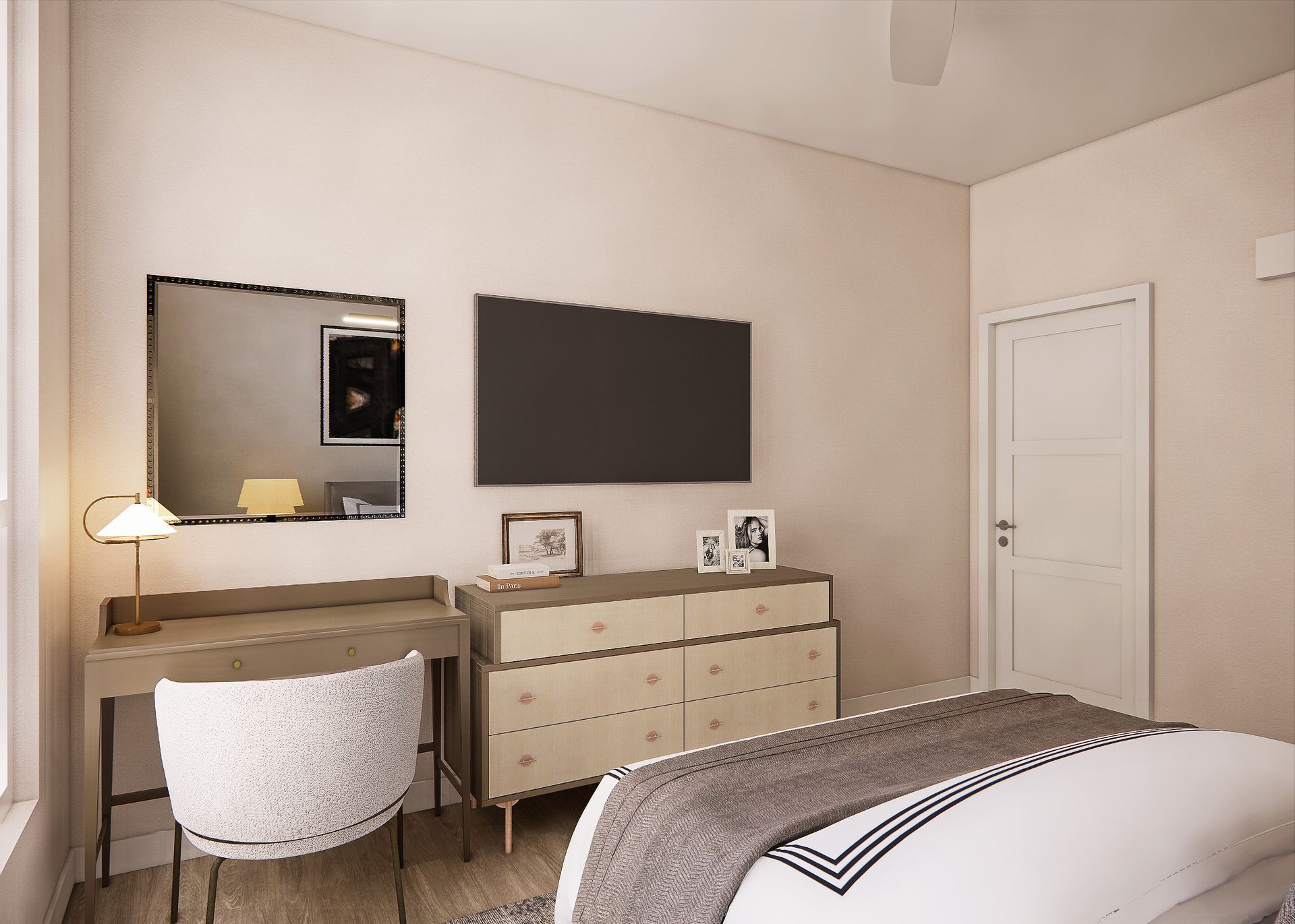 A bedroom featuring a desk with a lamp, a white patterned chair, a wooden dresser, a television, and a white closed door.