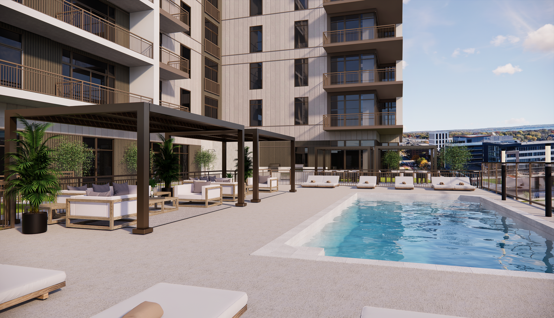 Pool and lounge area on a building rooftop. White couches, sunbeds, blue pool, and city views.