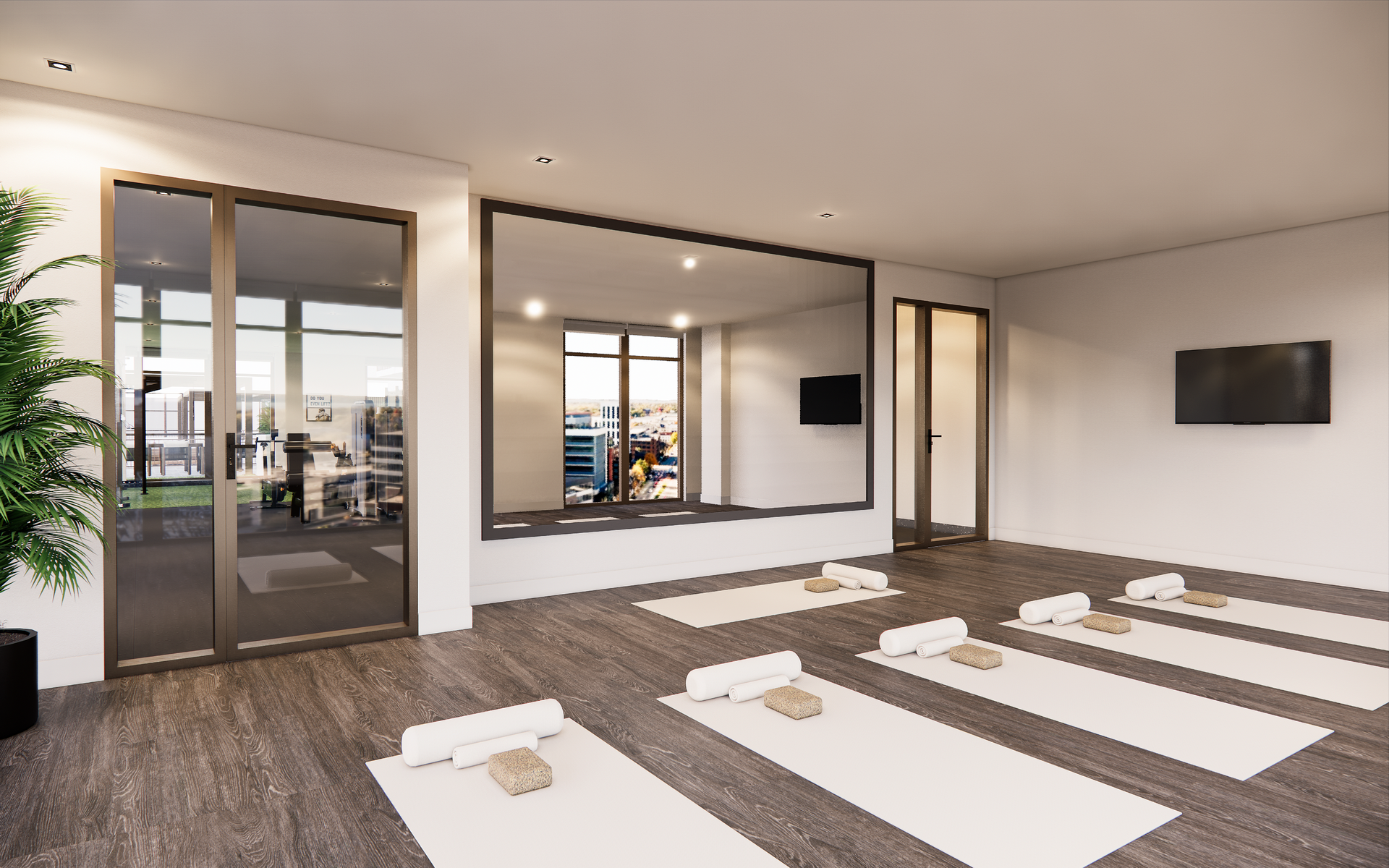 Yoga studio with mats, large windows overlooking a city, and a full-length mirror.