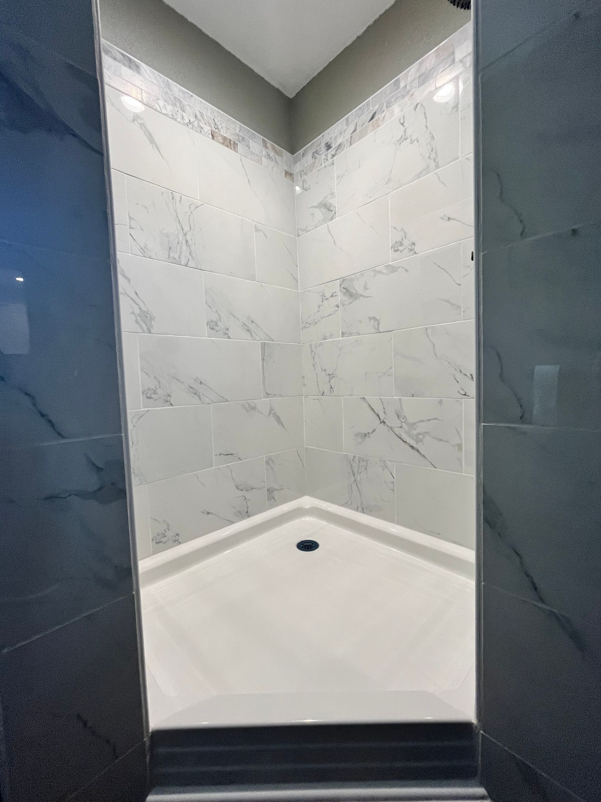 A bathroom with marble tiles and a walk in shower.