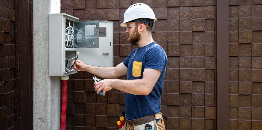 A man is working on an electrical box on a pole.