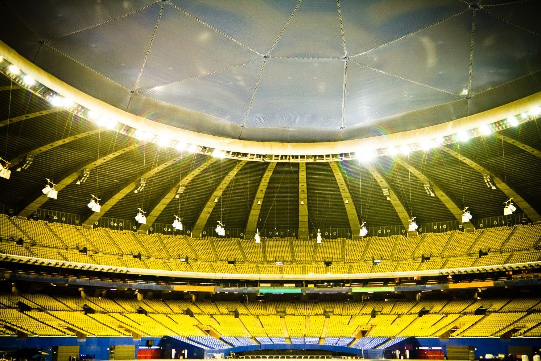 A stadium with a lot of yellow seats and lights on the ceiling.