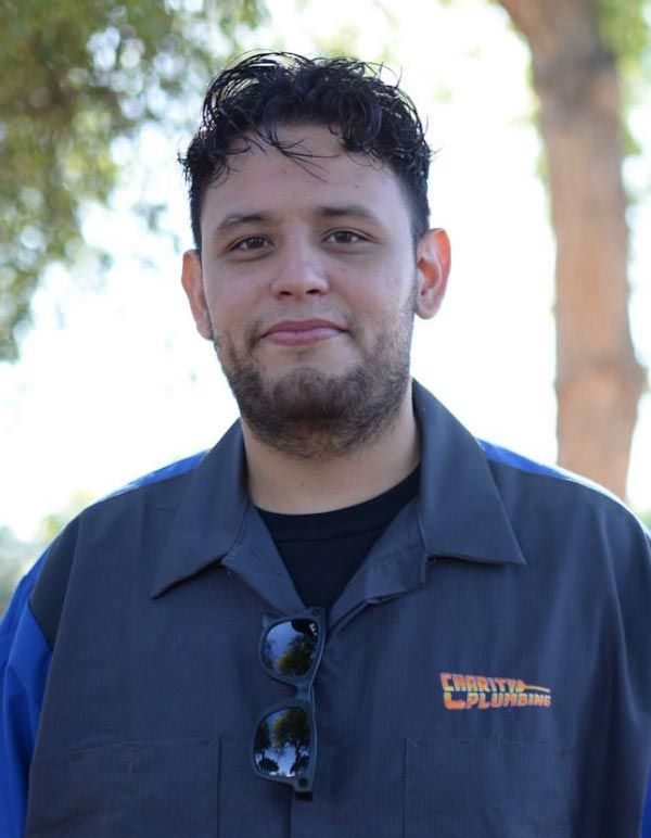 Man with short dark hair and goatee wearing a uniform, outdoors, with sunglasses on his shirt.