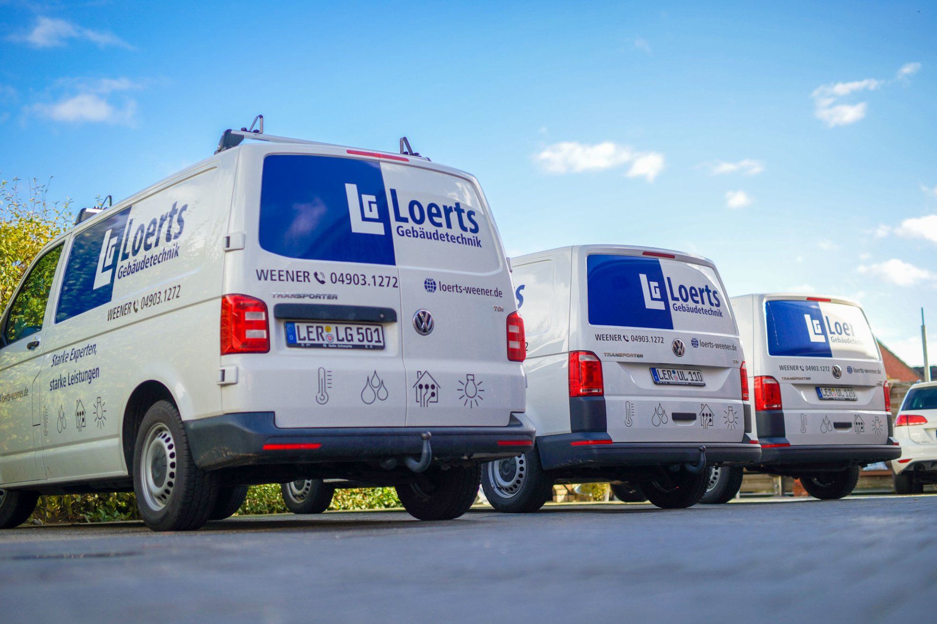 Drei weiße Lieferwagen stehen nebeneinander am Straßenrand.