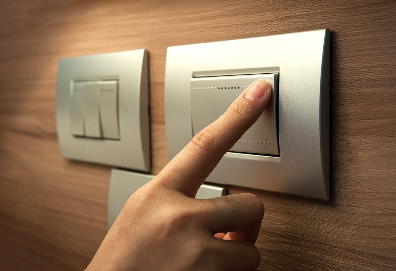 Eine Person drückt mit dem Finger einen Lichtschalter.