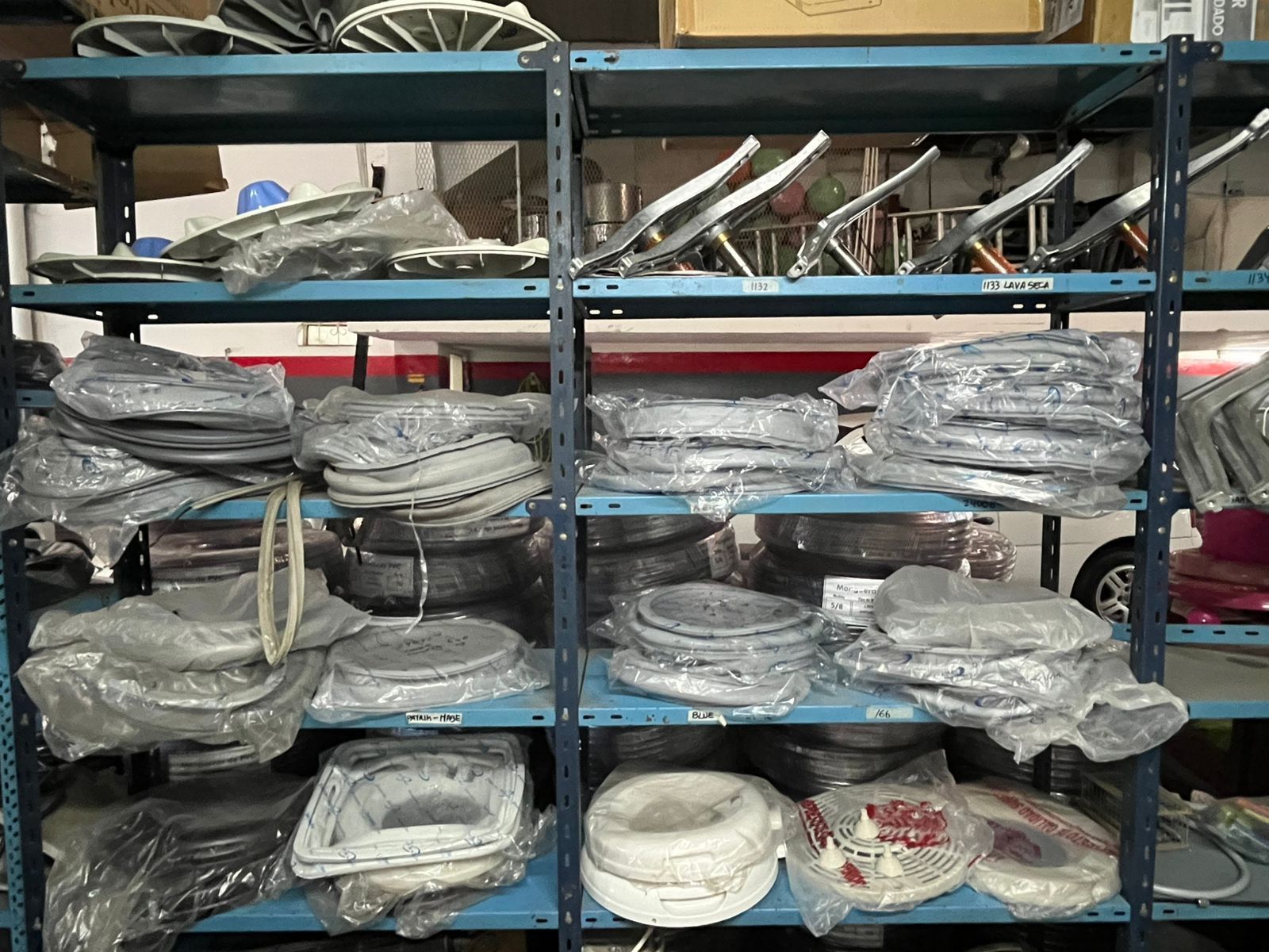 Estanterías repletas de piezas metálicas envueltas y cables en un trastero.