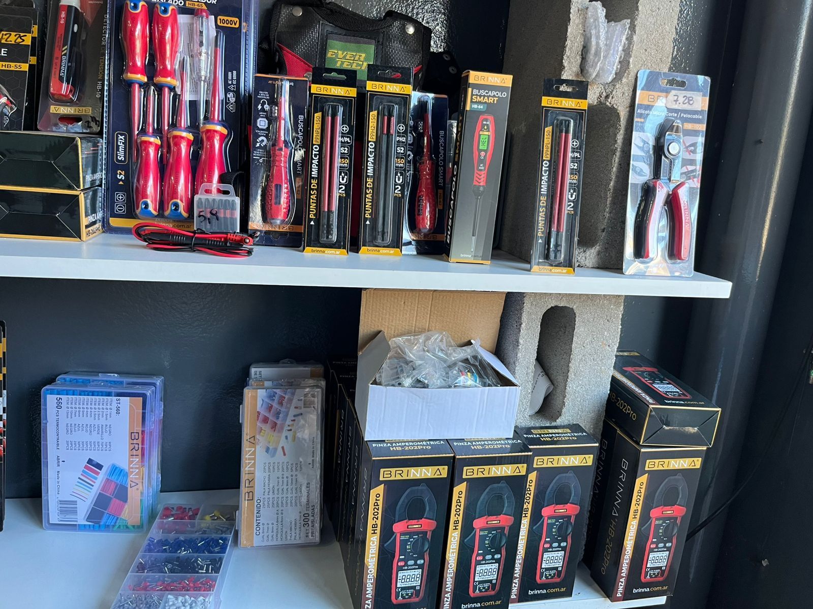 Estanterías repletas de herramientas manuales y alicates en cajas, expuestas en una tienda.