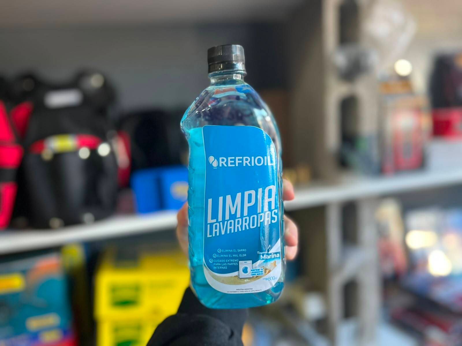 Botella azul de Limpia Fregones en el estante de una tienda, con productos borrosos al fondo.