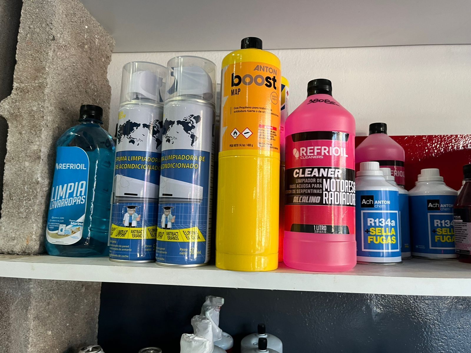 Estantería con botellas surtidas de productos de limpieza y cuidado personal en colores azul, amarillo, rosa y rojo.